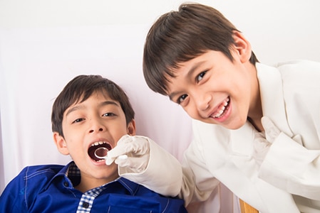 vLittle sibling boy pretend as a dentist close up inside mouth